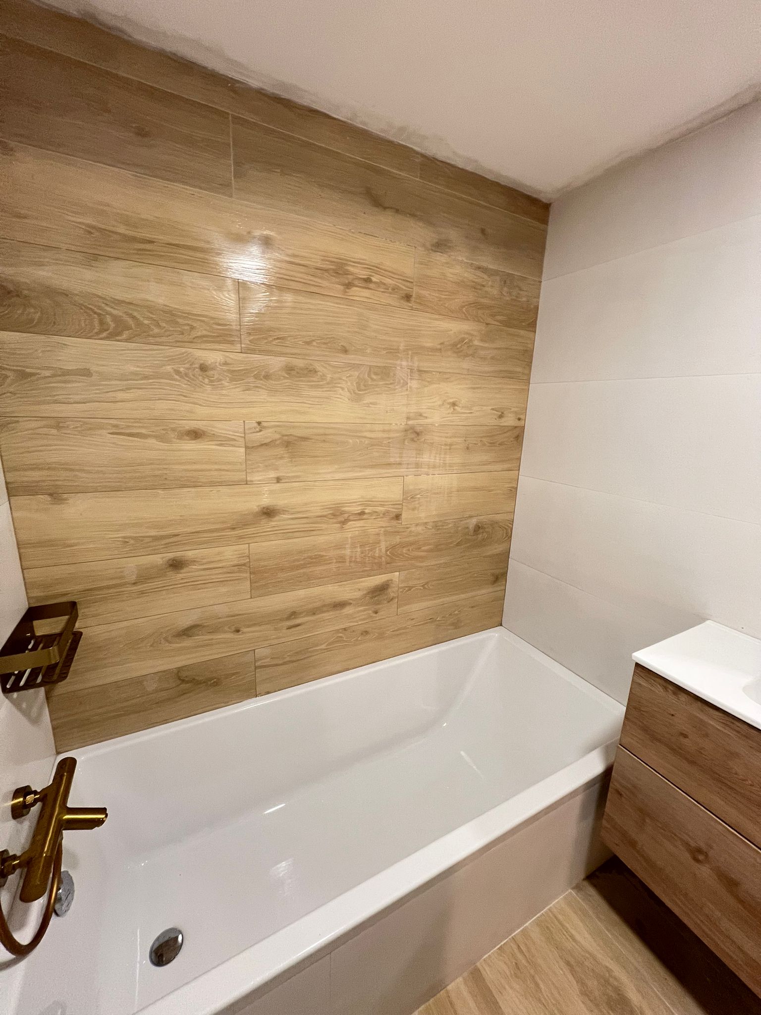 Bañera con azulejos imitación madera y grifería dorada